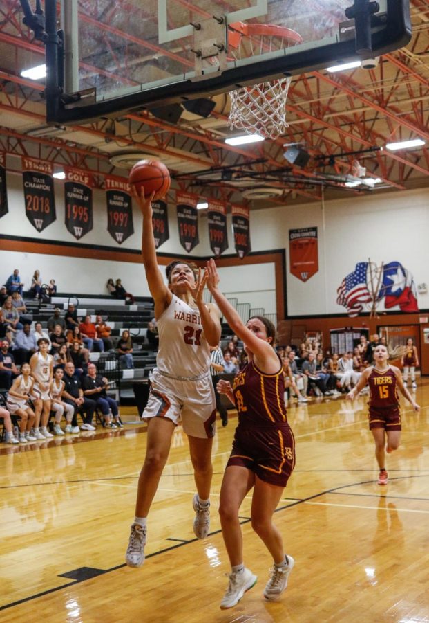 Reaching past her opponent, Victoria Brown 23 shoots a layup. Brown was notorious for driving the ball down the court and scoring.  
