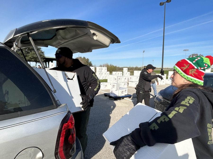Captains with the Travis County Sheriffs Office Corrections Bureau load packages of toys, books, food, and games into a car. The Travis County Sheriffs Brown Santa program is a non-profit run by law enforcement officers, other government employees, and community members.