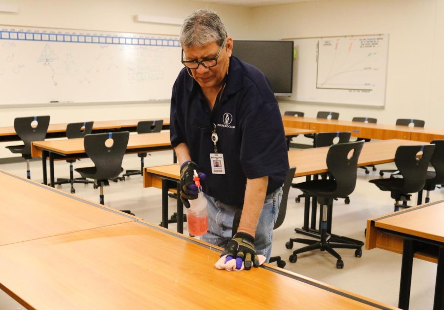 Spraying disinfectant, night custodian Pedro Minan wipes down tables in a classroom. Minan is new to Westwood, having worked at the school for less than one year. 