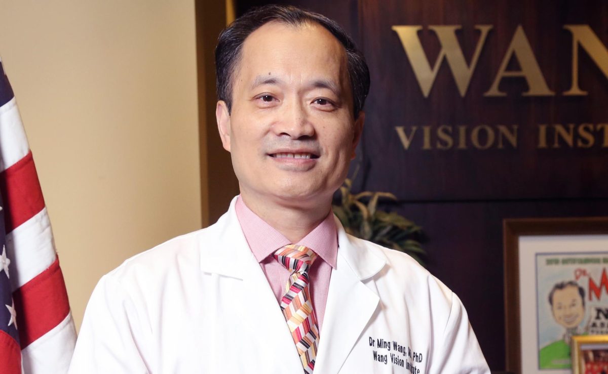 Smiling+in+front+of+his+company%E2%80%99s+front+desk+and+the+U.S.+flag%2C+Dr.Wang+stands+proud+as+an+Asian+American.+For+the+past+23+years+in+Nashville%2C+Tennesse%2C+Dr.+Wang+has+worked+hard+to+restore+the+sight+of+patients+nationwide+and+beyond.+