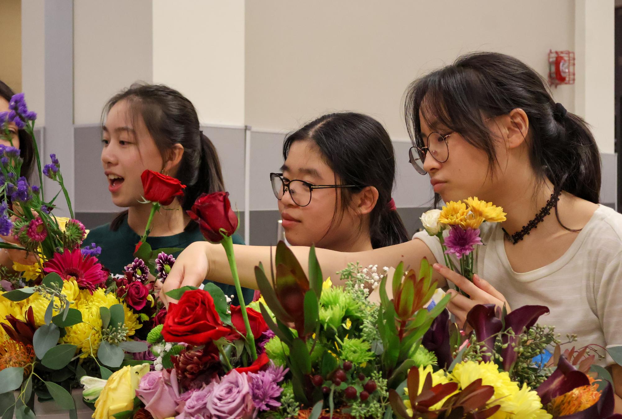 Gathering flowers, sophomores Karen Chen, Iris Chen, and Avery Chen make bouquet arrangements to take home. The flowers were brought to Grateful Gathering by a parent volunteer, and bouquet-making was the last activity of the event.
