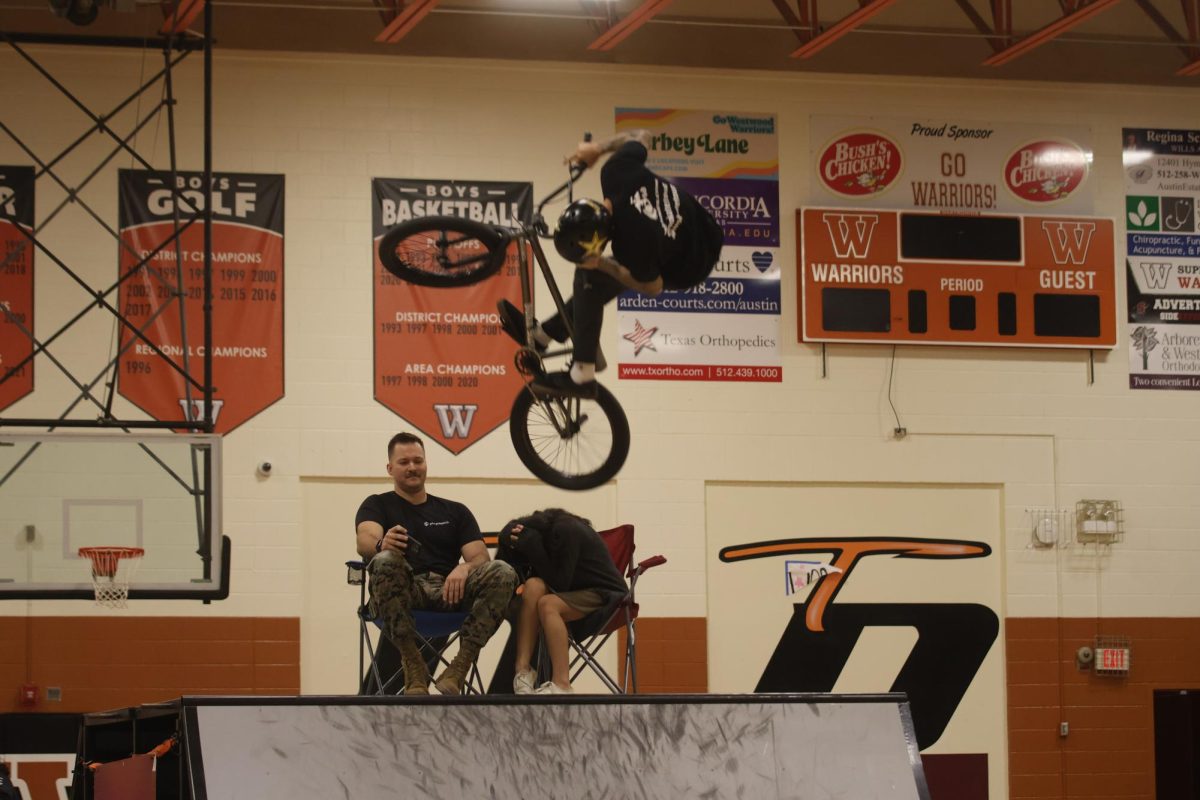 Gliding mid-air, a BMX rider jumps over Staff Sergeant Shawn Anderegg, USMC, and Spanish teacher Blanca Badillo during the second assembly. Sra. Badillo was chosen at random to be in the spotlight for this stunt.