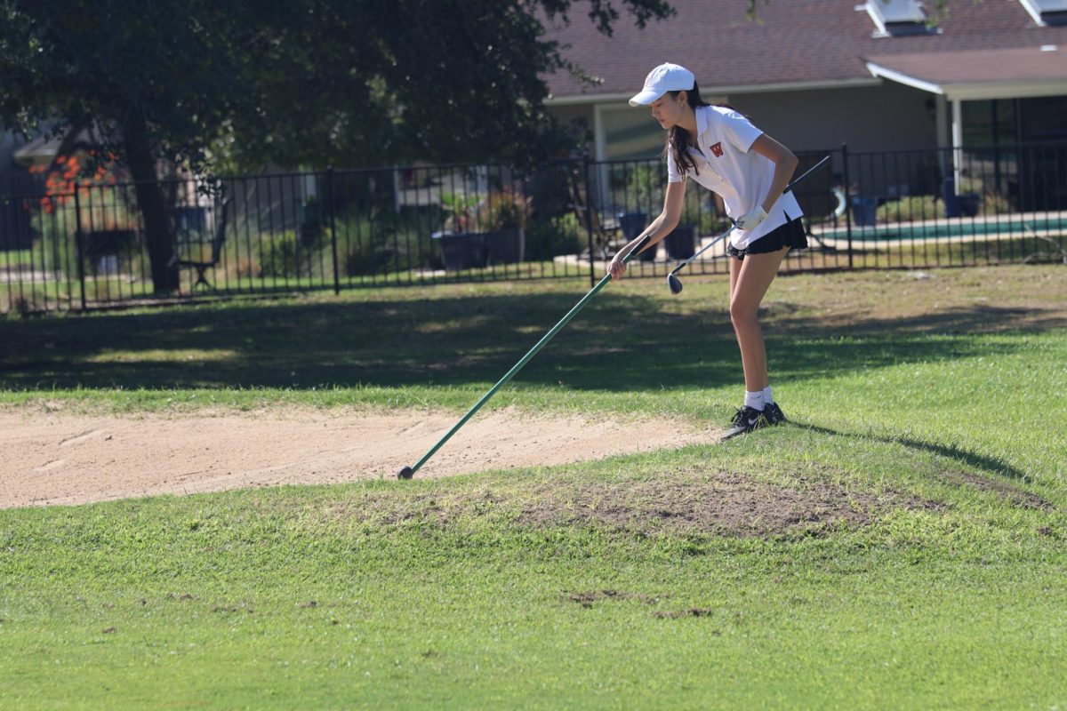 After successfully hitting her ball out of a sand pit, Brandee Benson 24 smooths the sand over for other players. As the captain of the JV Girls golf team, Benson believes that a more united golf team will have a stronger ability to persevere through challenges.