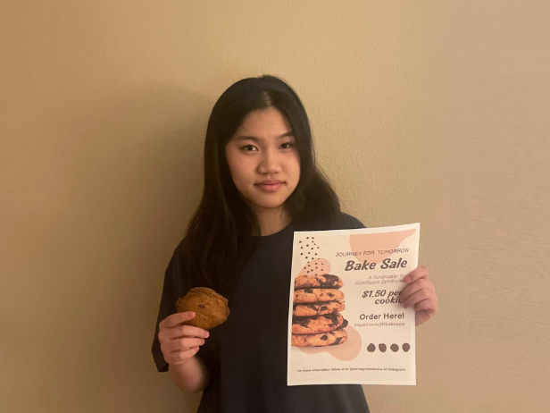 Posing+with+a+cookie+and+flyer%2C+Sophie+Liu+25+makes+up+half+of+Journey+for+Tomorrow%2C+a+HOSA+project+that+aims+to+raise+funds+for+Sanfilippo+syndrome+research.+To+encourage+donations+to+their+cause%2C+Liu+and+her+HOSA+partner%2C+Jenny+Yun+25%2C+created+flyers%2C+fundraisers%2C+and+social+media+accounts.+%5BFunds+are%5D+going+towards+genetic+research+for+gene+therapy+and+enzyme+replacement+therapy+so+that+there+can+be+a+cure+for+Sanfilippo%2C+Liu+said.