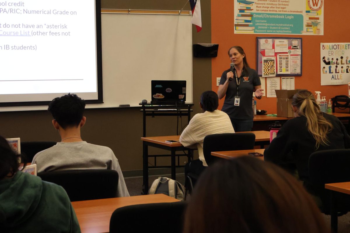 At+an+informational+meeting%2C+IB+counselor+Ms.+Ann+Castro+tells+assembled+students+about+the+process+of+signing+up+for+ACC+classes.+These+mandatory+meetings+were+offered+to+students+during+lunch.