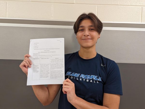 Smiling, Nathan Paddock 25 holds up a high-scoring homework assignment. The issue of grade inflation has persisted since the nationwide lockdown in 2020, increasing competition and leading to grades that may not reflect students academic abilities.