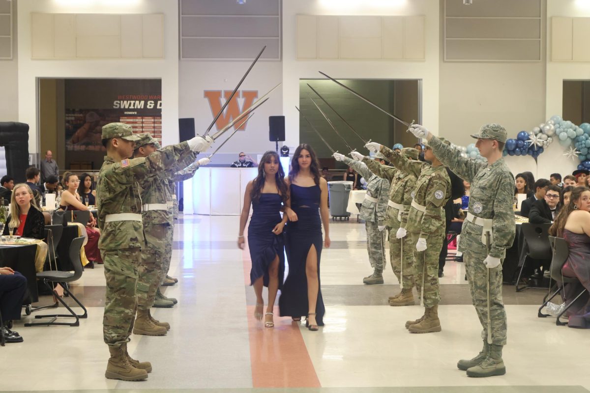 Escorted by her friend C/AB Myah Kapavik 27, C/TSgt Aliyah Mohammed 24 walks through the saber arc. Senior cadets were recognized during the ball by walking through the saber arc.