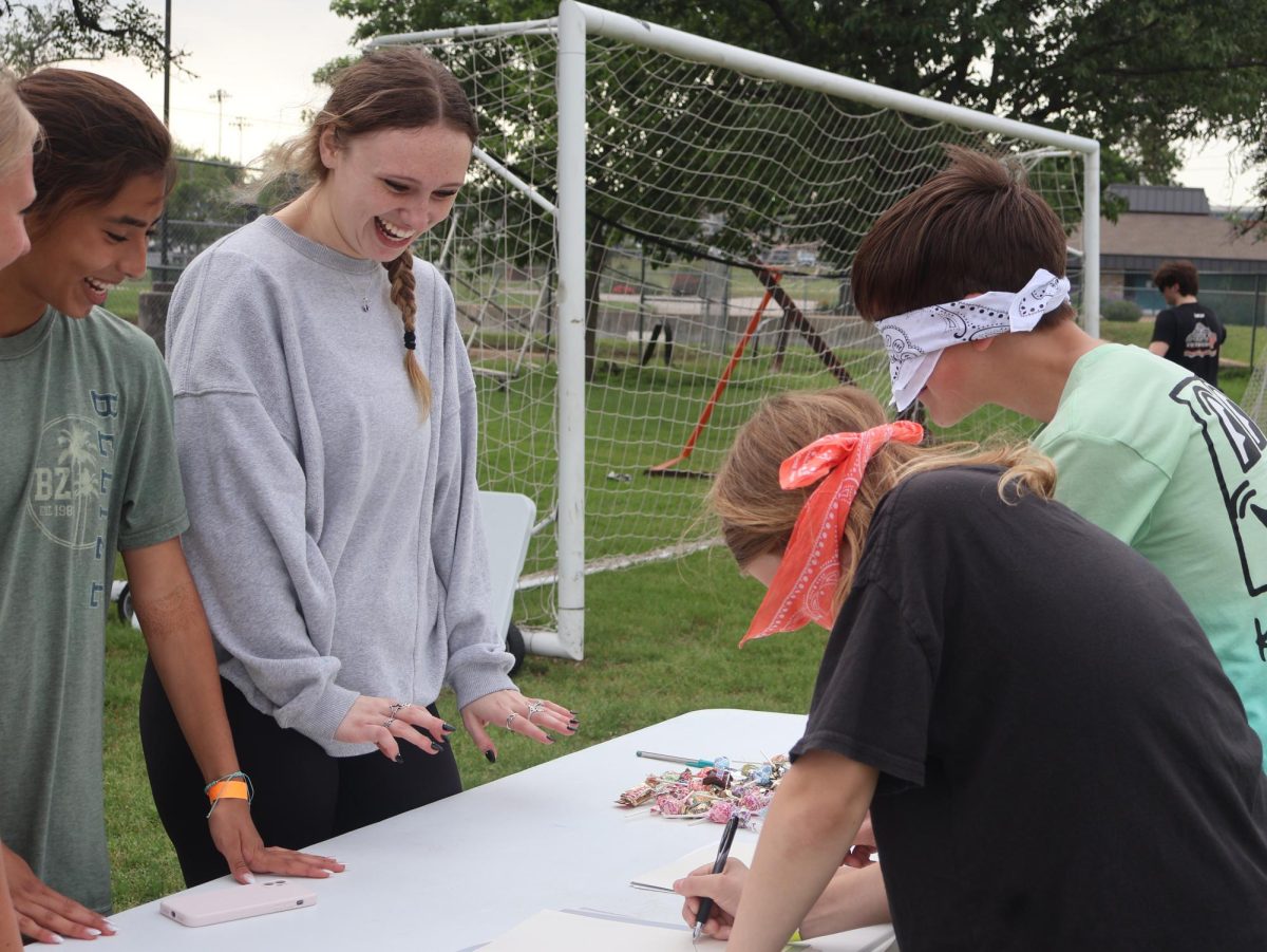 Aubrey Matthews 25 and Natalia Llano 25 facilitate blindfolded drawing at the Ceramics Club booth. Ceramics Club handed out candy prizes to anyone who could successfully draw while blindfolded.
