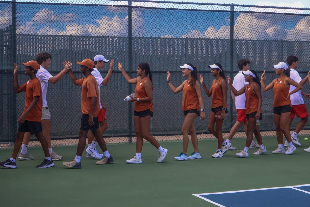 Ending the match, the varsity tennis team forms a line to high-five Westlake High School's tennis team. Westwood remained undefeated with a final score of 16-2.