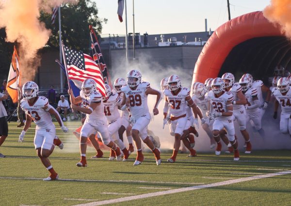 Bursting out of the tunnel, the Warriors hype themselves up preparing for a game against the Cedar Ridge Raiders on Friday, Sept. 21. The Warriors went on to throw a touchdown pass on their opening play instantly giving the Warriors the upper hand. "Each week we come out on the field to do what we practiced during the week" Coach Anthony Wood said.