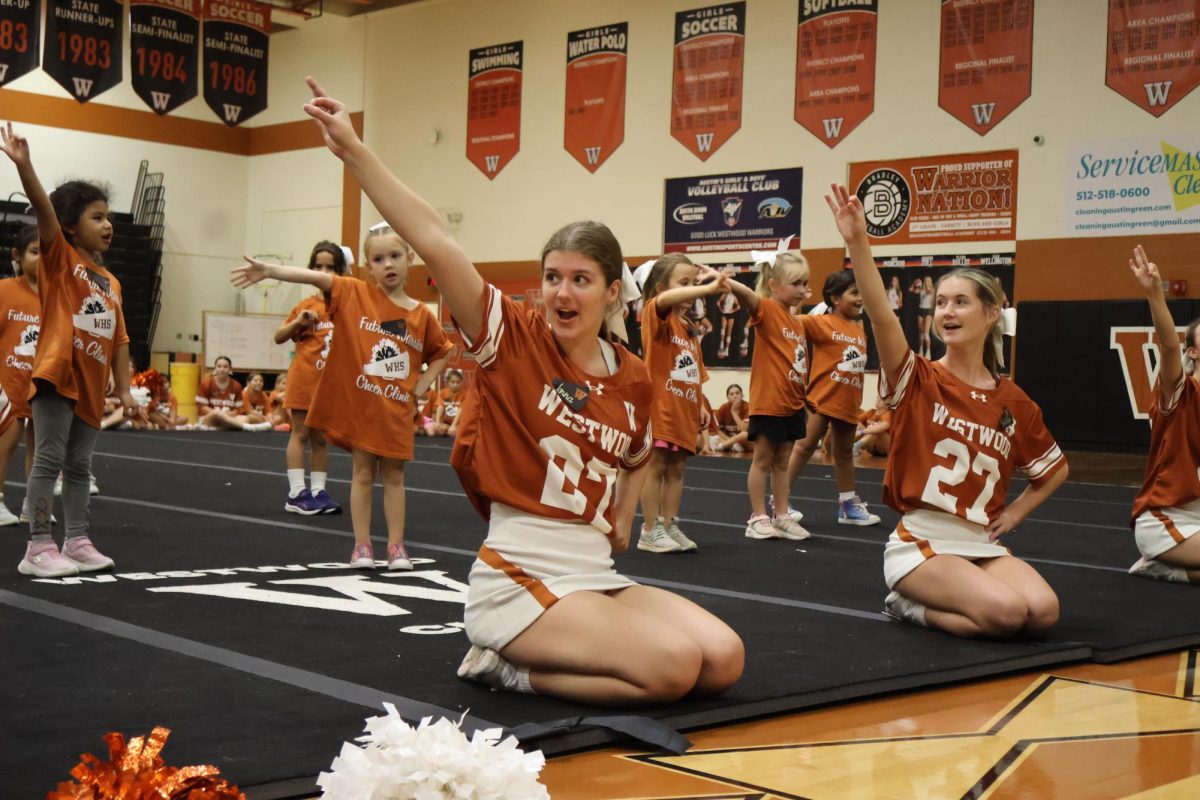 Cheerleaders Jenna Hallidy ‘27 and Katelyn Wiley ‘27 guide mini cheerleaders to shout their school chant, ‘Fight Warriors Fight!’ The mini cheerleaders put their new knowledge to use when showing their parents the tricks and chants that the cheerleaders taught. “When I came here as a mini I really looked up to the cheerleaders and I hope I can leave as good of an impact on the children I’m watching as the cheerleaders did on me,” Wiley said.