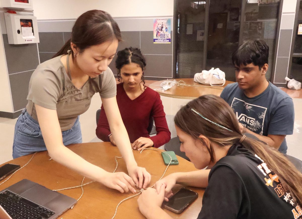 Teaching a member how to assemble the knots for the lanyard, Vice President Bailey Zhang '25 demonstrates how to create a complete paracord lanyard to Kyla Cretencio '28, while Secretary Naomi Kini '27 and Zephan Momin '25 watch. Zhang and Kini co-organized the lanyard-making event, and guided club members in crafting the lanyards.