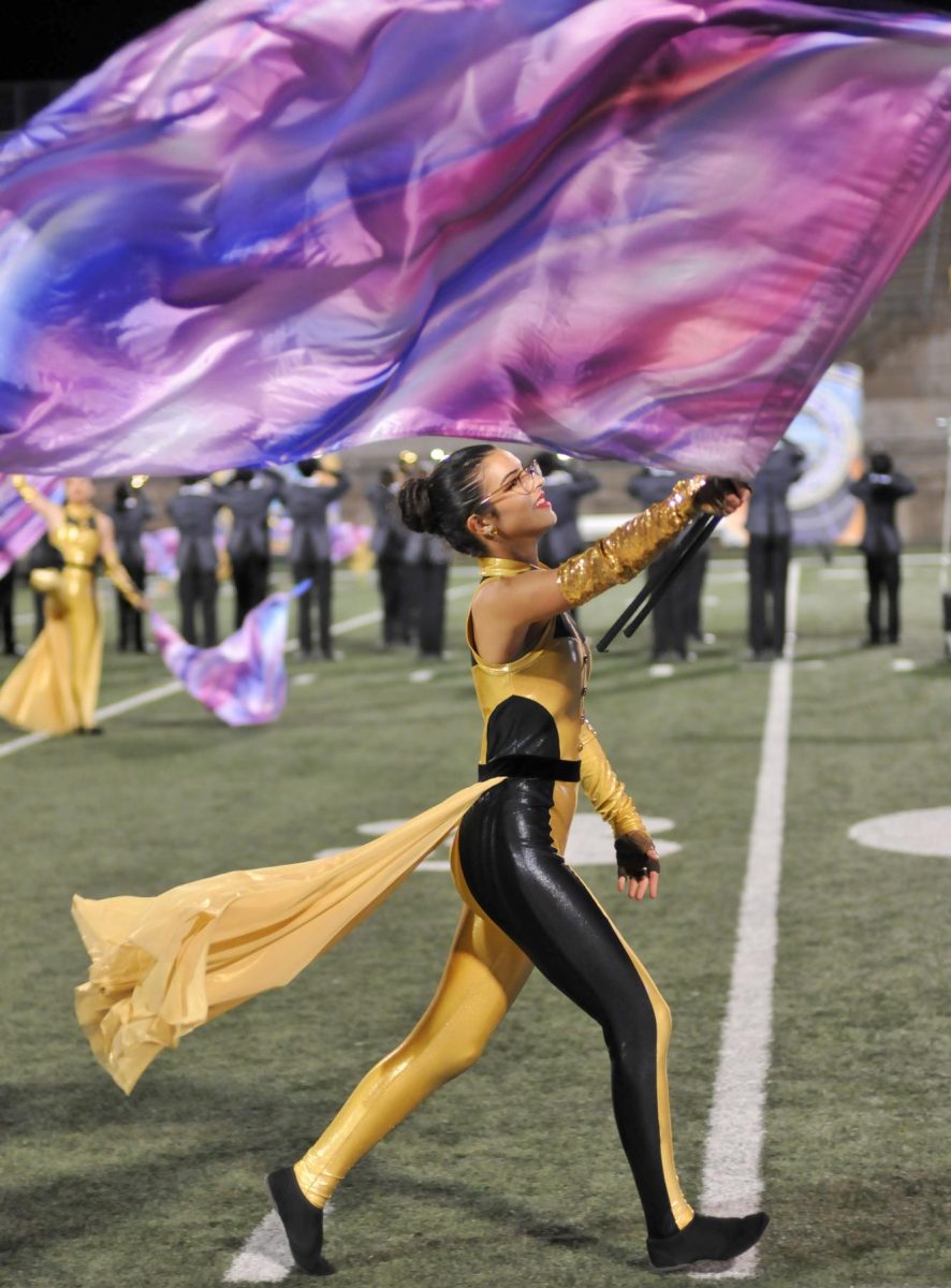 Skirt flowing behind her, Abi Caudle '26 spins her flag. The guard uniforms were designed by Jim Moore to look elegant and grand.