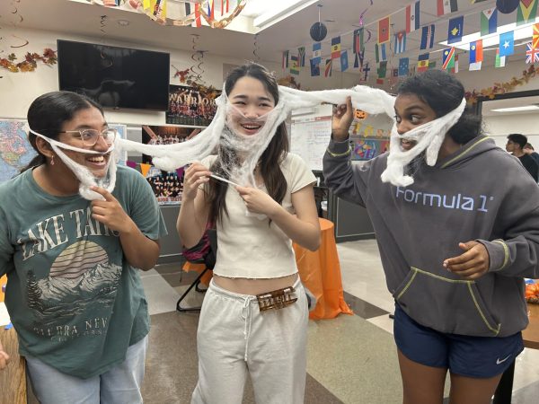 Finding new uses for the cotton cobweb decorations, seniors Anika Anumalla, Jennifer Rong, and Tharini Murugananth put together a makeshift costume for the costume contest. Part of the many events at the social, the winners of the costume contest received IB merch as a prize. 