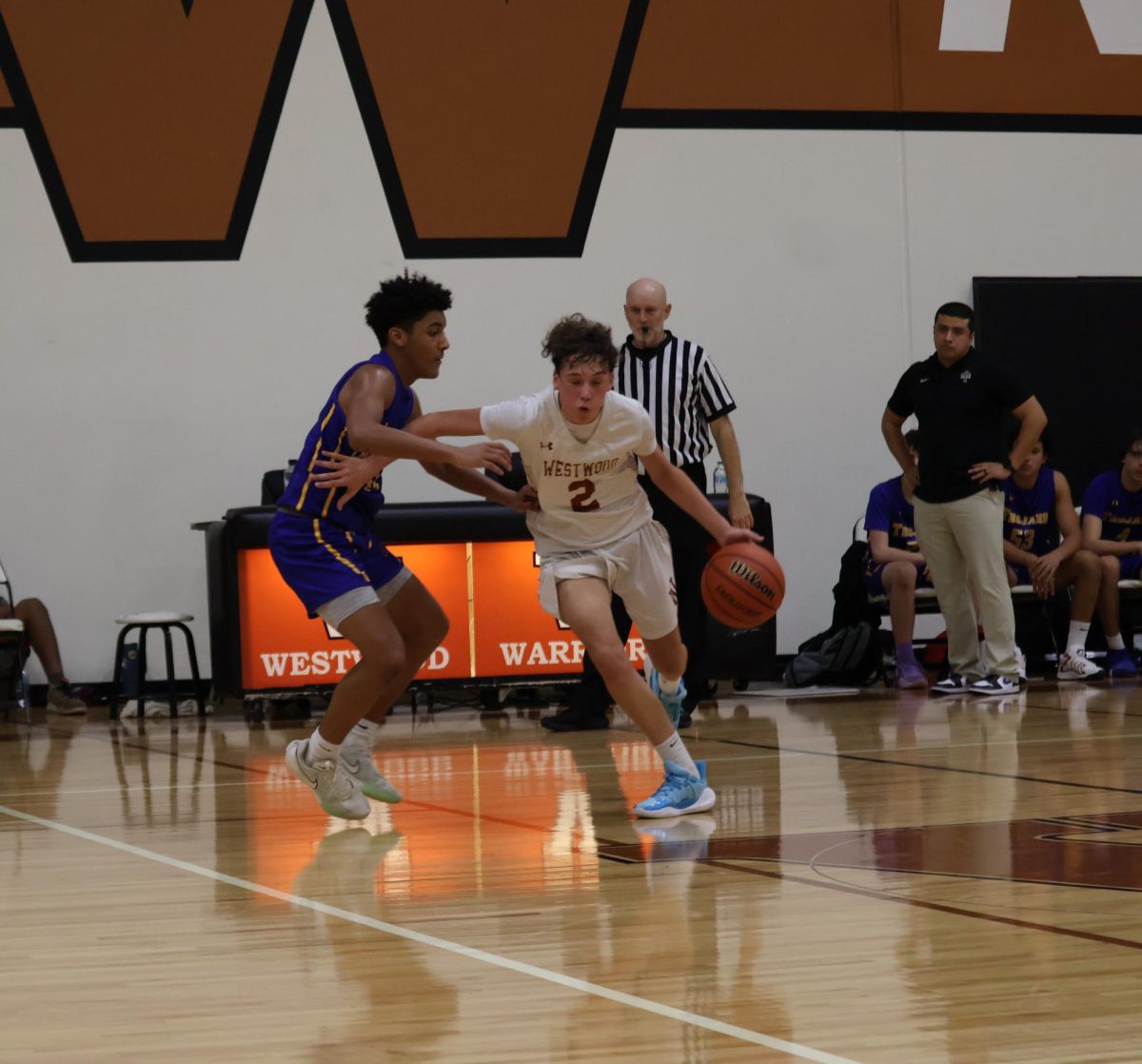 Pushing his opponent away, Miles Fustes '28 runs the ball down the court. The Warriors managed to continue scoring throughout the whole game.