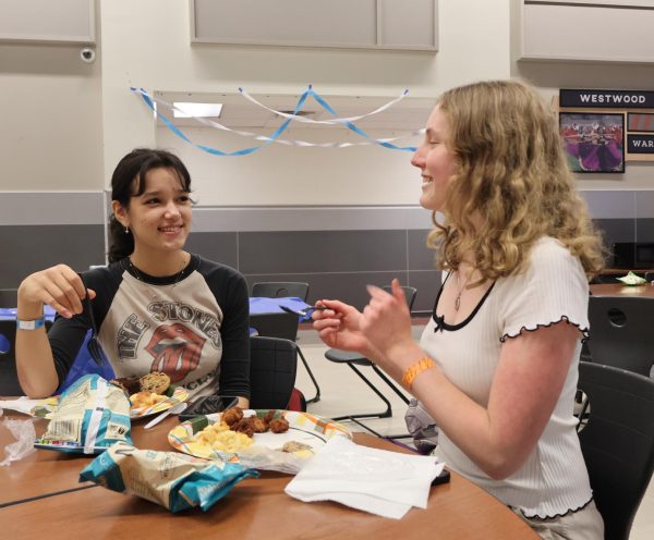 Smiling, Zeren Johnson '25 and Nina Jovanovic '25 socialize and reminisce on their EE experience while eating dinner. The dinner was catered by Chick-fil-A and there was a wide array of other food such as fruit, chips, and sheet cake. 