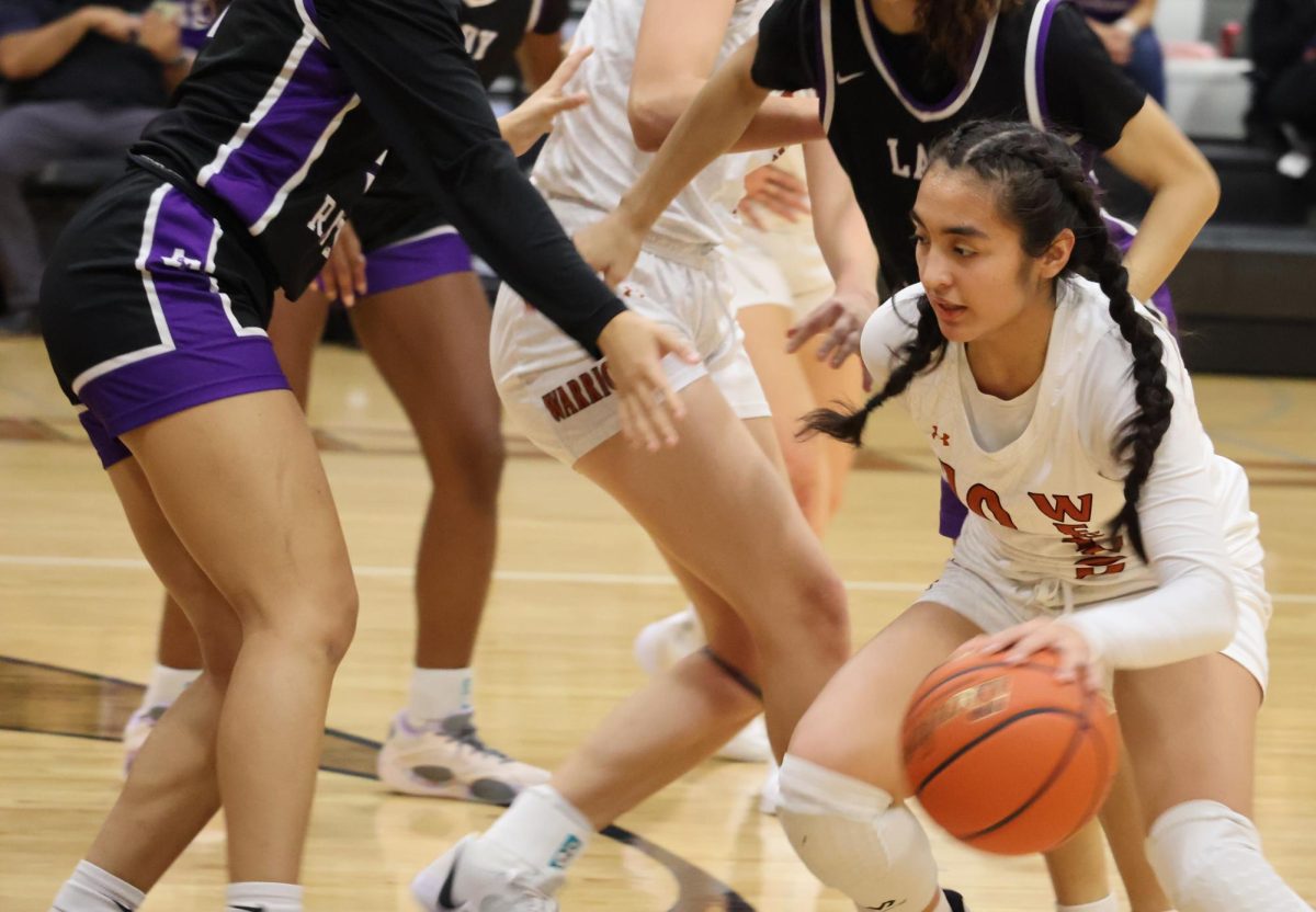 Crouching, Bella D'Alessandro '25 evades her opponents. D'Alessandro drove the ball down the court toward San Marcos's goal, but the Rattlers' defense held strong.