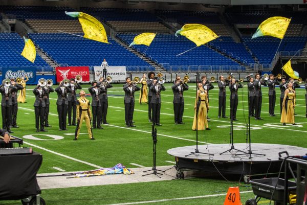 Tossing their flags in unison, members of the Color Guard stand with the band as they line up in their company front. During a company front, the whole band forms a line and marches side by side across the field.