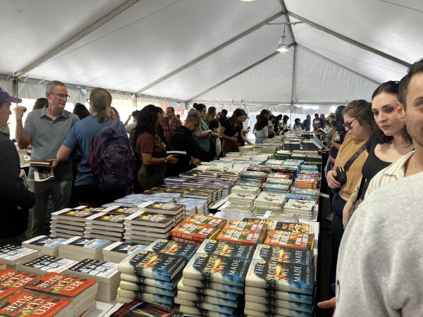 Texas Book Festival attendees crowd around a table of books. In the book purchasing tent, sponsored by BookPeople, attendees could buy the books of the attending authors.