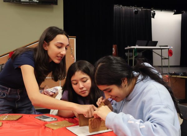 Each holding part of their gingerbread house, Juniors Anushka Gupta, Emma Rincon, and Atiriya Banerjee work to construct a gingerbread house worthy of winning the competition. 