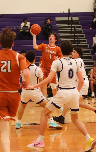 After taking a hit, John McNair '26 jumps above his defenders into the paint, trying to deepen the Warriors' lead over the Cedar Ridge Raiders on Tuesday, Dec. 3. McNair, after his time on the freshman team as a leading scorer joined the varsity team in his sophomore year in the hopes to continue his yearly tradition of layups, free throws, and buckets. "The way that we play [and succeed] does not matter what the other team looks like," Coach Rigney said. "We are just going to play the same way as we do."