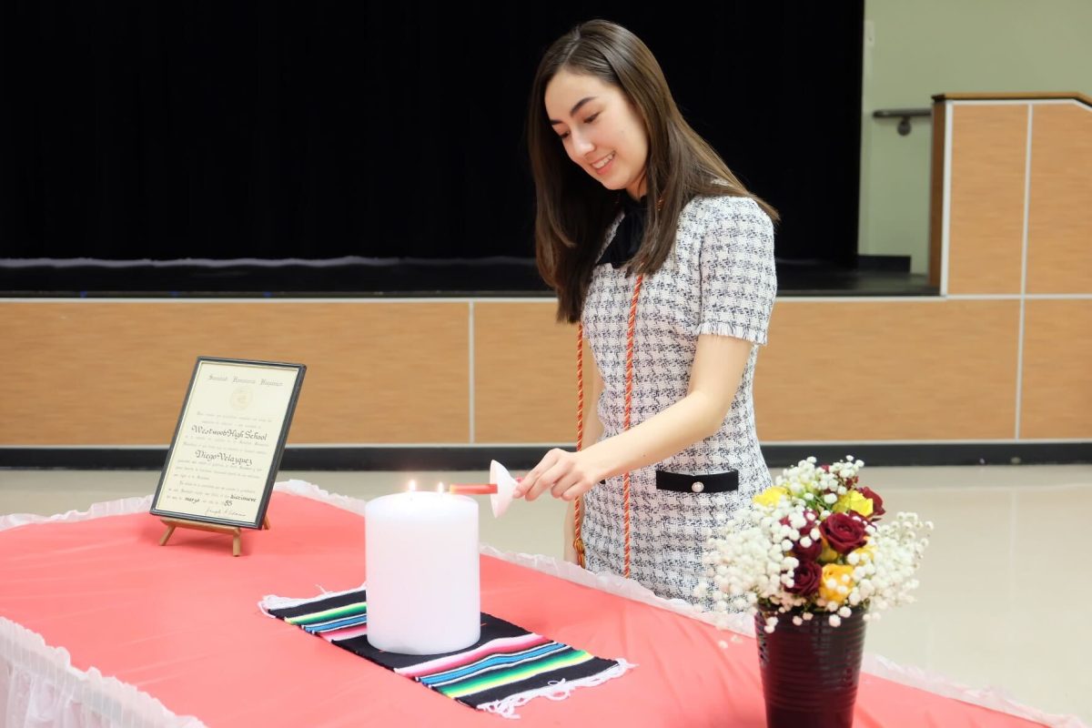 Lighting a candle, Arden Choi '26 takes part in the ceremony. After swearing the induction oath, members blew out the candles as a symbol of their induction into the organization.