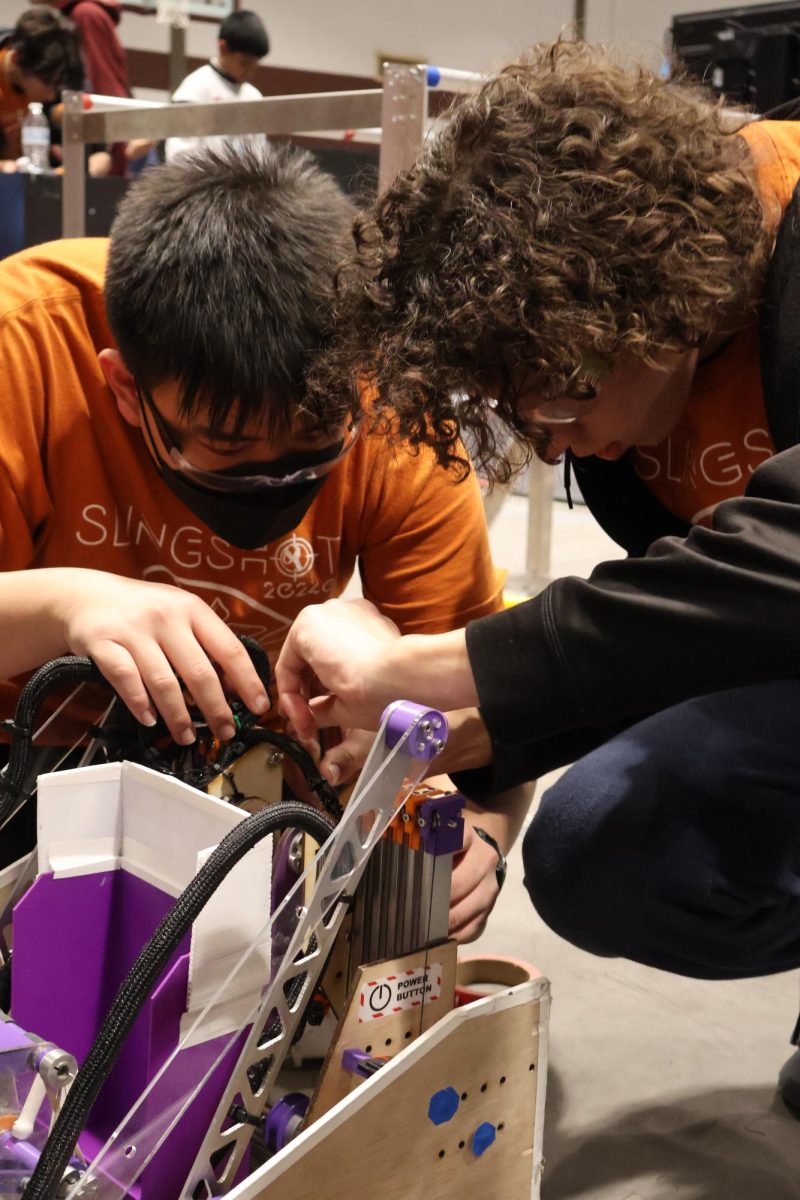 Focused, Jihoon Im ’26 and Scott Sundstrom ’25 of team Slingshot repair a broken component of their robot. The component broke while they tested their robot in between elimination matches, making it critical to get the robot working in time for their next match.