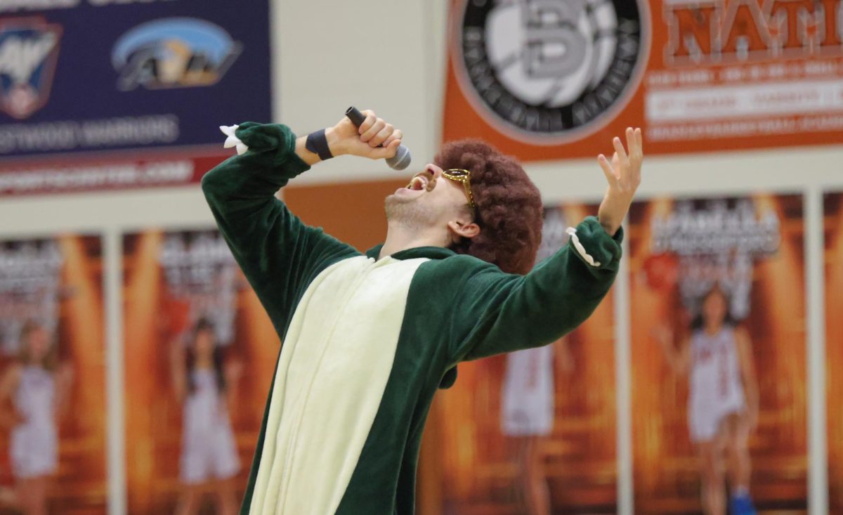 Donning a wig and mustache, Mr. James Cox lip syncs to 'Beautiful Things' by Benson Boone. Mr. Cox did a knee slide at the end of his performance as the crowd waved phone flashlights to the beat. 