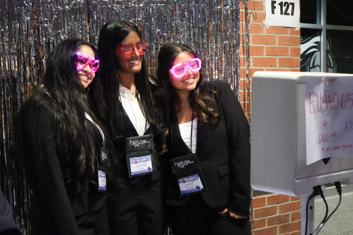 Smiling with friends, Tisya Dave '27 poses for the photo booth. A new aspect of the conference was a photo booth with Area 1 pink-themed props, where members could capture their memories.