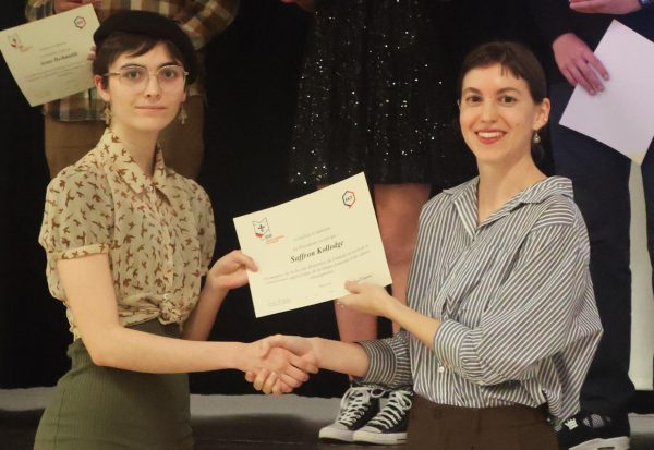 Shaking hands, Saffron Kollodge '26 receives her induction certificate. Each inductee received individual recognition throughout the event. 