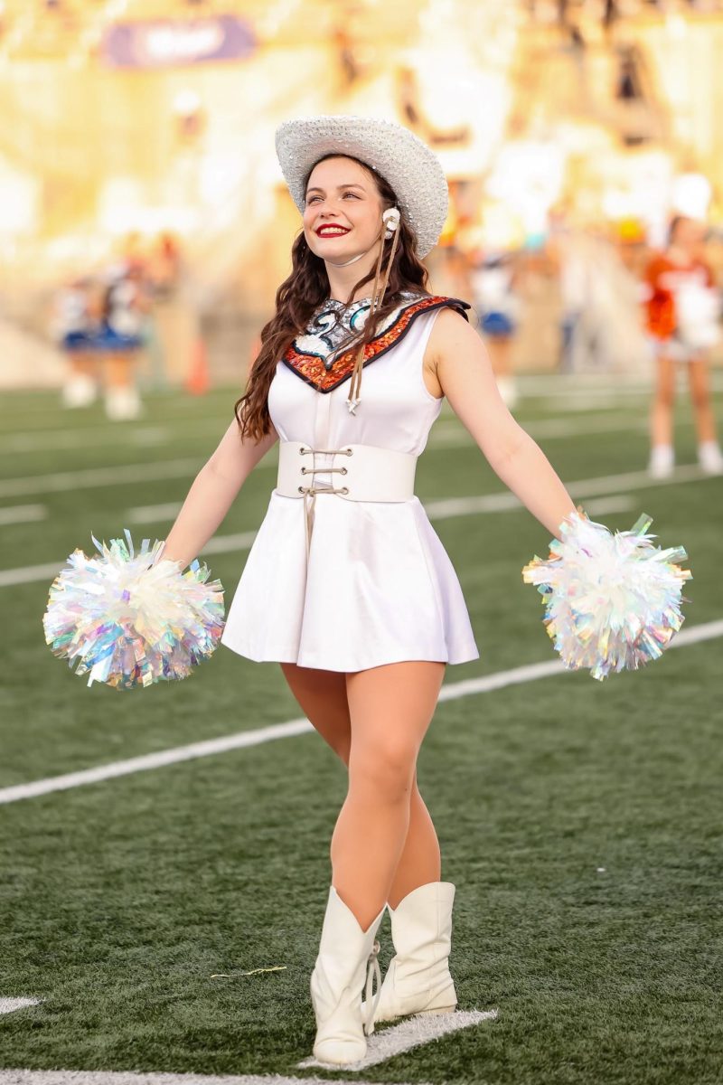 Clasping two pom poms, Polly Nickens '25 strikes a pose. Holding the title of Major, Nickens has contributed immensely to the Sundancers. "It's such a great opportunity and I love getting to serve my team in the ways that I do. It's just the most incredible thing," Nickens said.