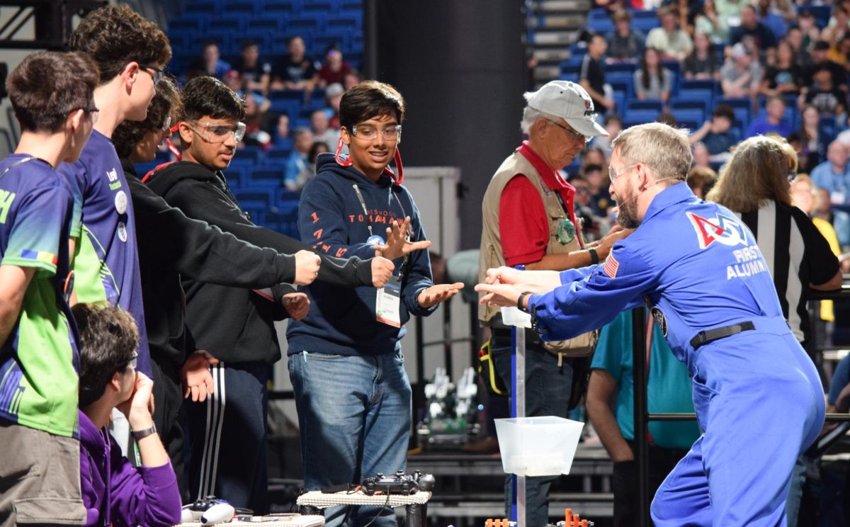Standing alongside team CSH from Timisoara, Romania, Satvik Chawla ’25, Aarush Srivastava ’26, and Souren Uchat ’26 play rock, paper, scissors with the game announcer. To keep things interesting during delays, announcers frequently told jokes or played games with the drivers.