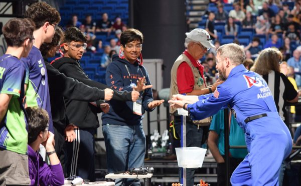 Standing alongside team CSH from Timisoara, Romania, Satvik Chawla ’25, Aarush Srivastava ’26, and Souren Uchat ’26 play rock, paper, scissors with the game announcer. To keep things interesting during delays, announcers frequently told jokes or played games with the drivers.