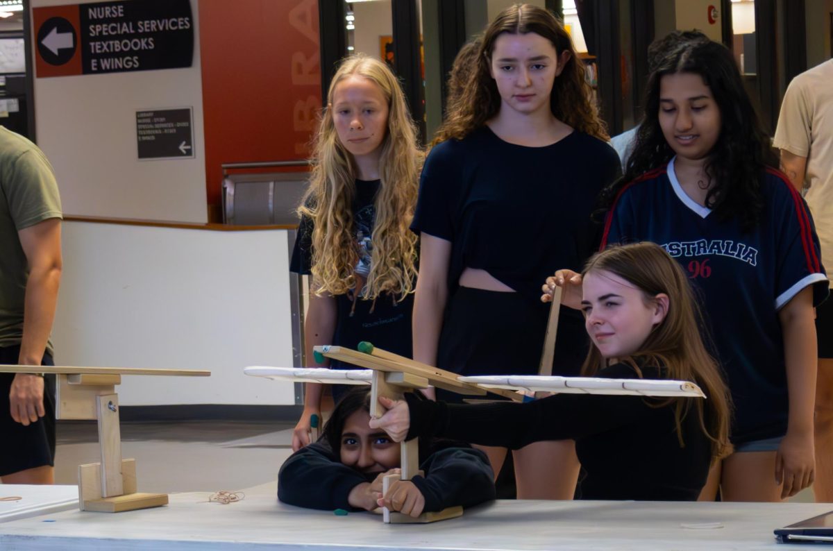 Getting ready for the perfect launch, Allie Jennings '27 aims her group's plane as juniors Audrey Cassidy, Shelly Bach, and Aanya Solanki watch. The Aerospace Engineering students applied technical skills when creating their plane.