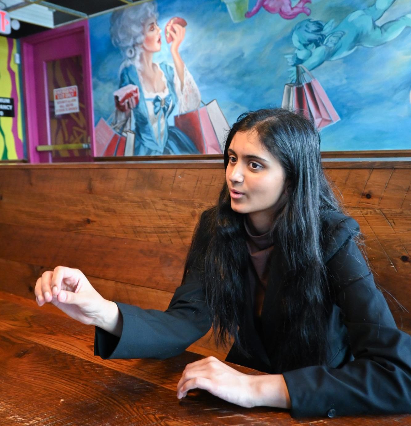Gesturing across the table, Aanya Ujjval '26 talks policy with a friend at a downtown restaurant while waiting to testify about the Texas Legislature's attempt to redistrict congressional maps. Aanya waited over four hours among dozens of others in an effort to make constituent voices heard on redistricting. 
