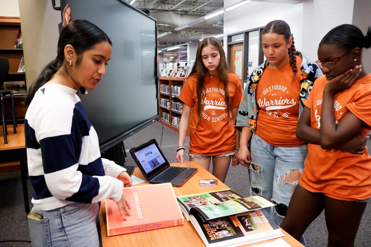 Flipping a yearbook shut, Aarya Kale '26 pitches the journalism pathway to a group of visiting eighth graders. As a change from previous years, the eighth graders visited specific program booths to learn about possible high school activities they could pursue. 