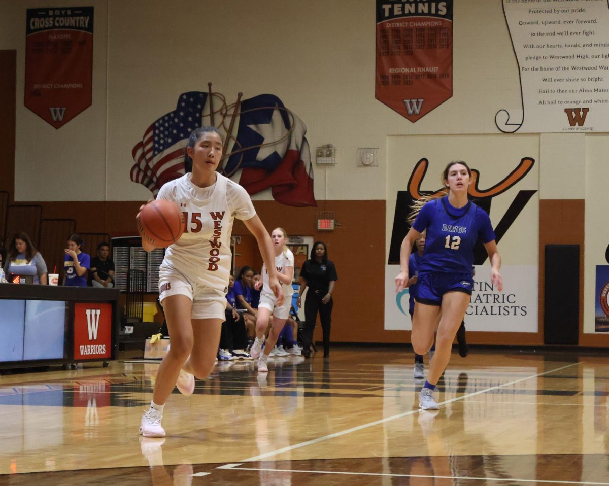 Iman Xu '28 dribbles the ball while running across the court to make a layup. Throughout the game Xu makes several layups. 