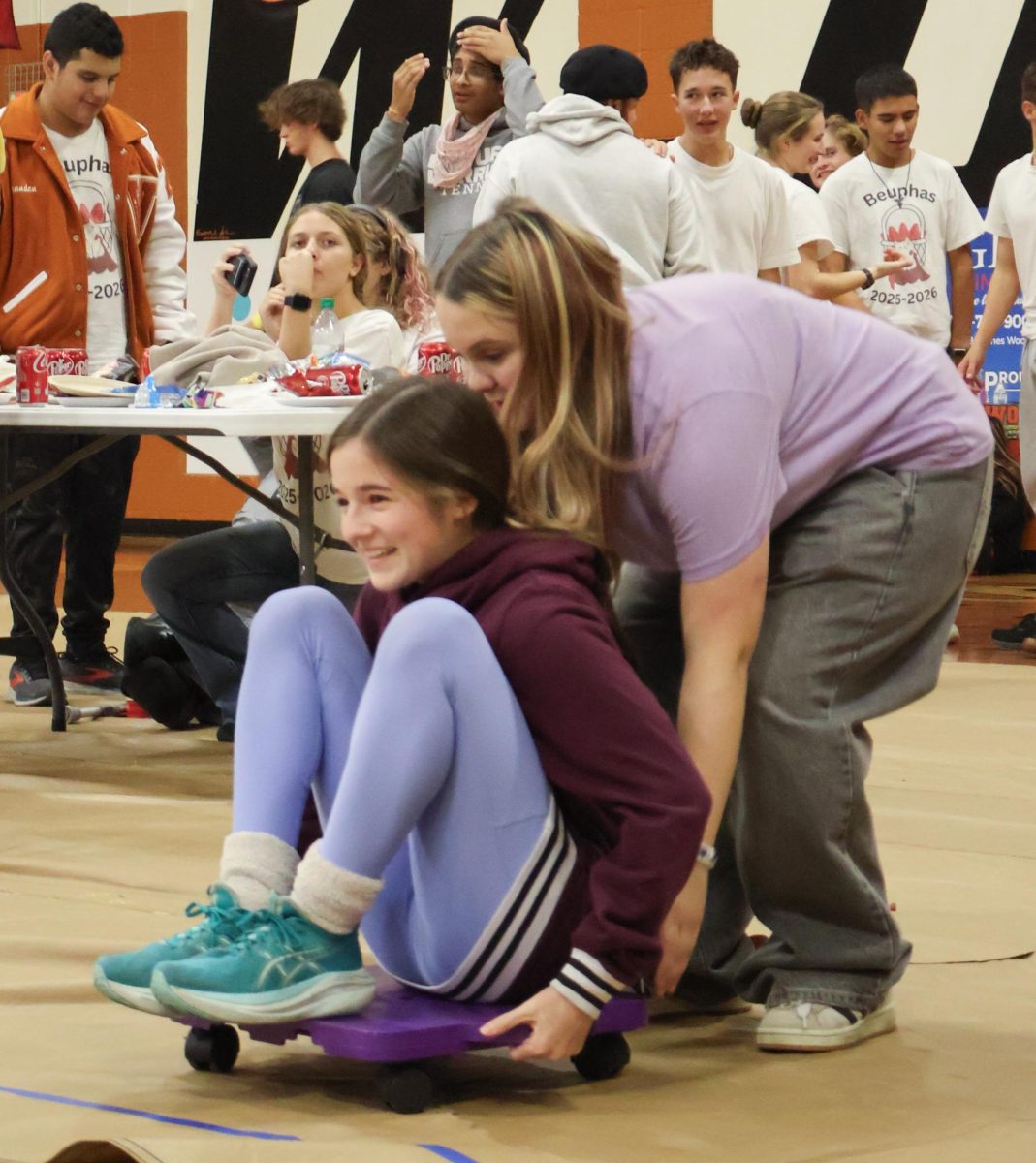 Holding onto her scooter, Lucy Petiprin '28 prepares to be pushed forward by her eighth grade partner. One of the favorite events was the human bowling, in which students rolled towards yoga mat bowling pins on scooters.