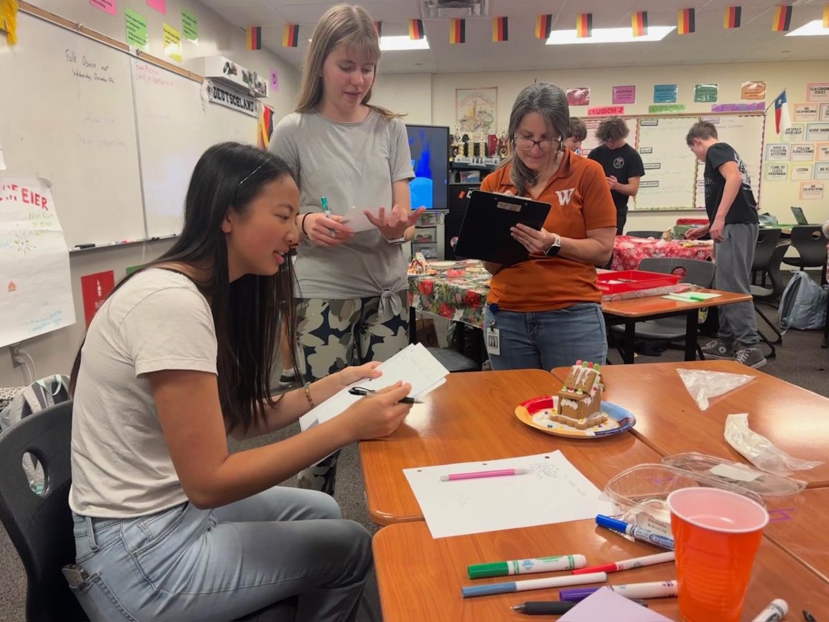 Gathering around a completed gingerbread house, judges Iris Wang '26, Ella Steinheider '26, and German Teacher Frau Melgar jotted down notes about the presentation of the house. The houses were scored out of 40 points based on aesthetics, creativity, and structure.