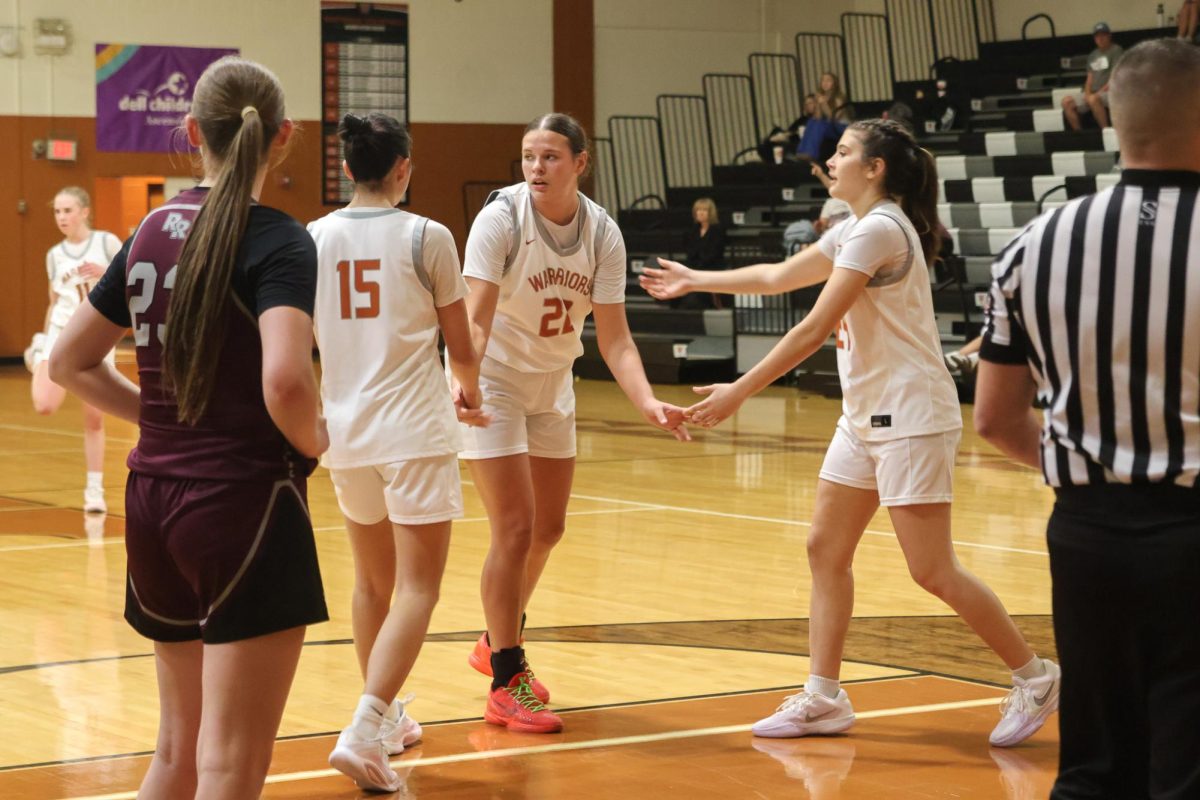 Emily Fry '29 reaching out to Lola Proano '26 and Iman Xu '28 as they regroup on the court during a pause in the free throw. Fry '29 was a key player for the Warriors and consistently contributed through strong communication and leadership during the game. Fry '29 helped guide her team as they reset and prepared to continue the matchup.