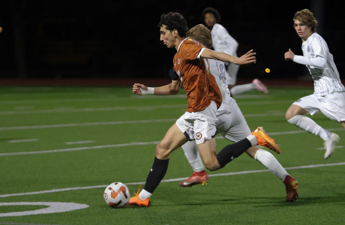 Sprinting past a Raider, Kaz Seyhoon '26 drives the ball towards the goal. The Warriors scored three times during the match: twice in the first half and once in the second half.