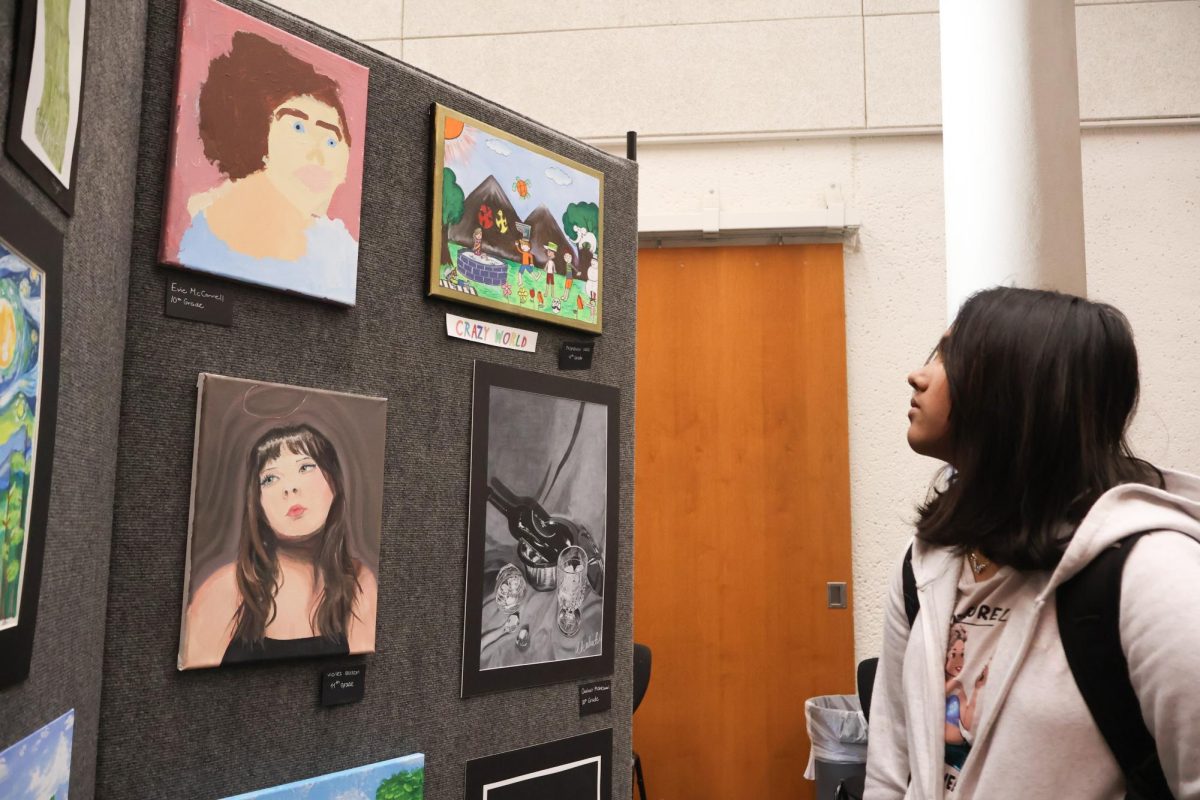 Invested in the wall of paintings, Diyashri Karthick '29 admires the different art expressions from the use of paint. Spectators roamed the exhibit, pointing out artworks that stand out to them. "I'm actually really proud of the work I submitted, and I don't know if I'll get these chances in other places so I'm glad I took this opportunity," Karthick said.