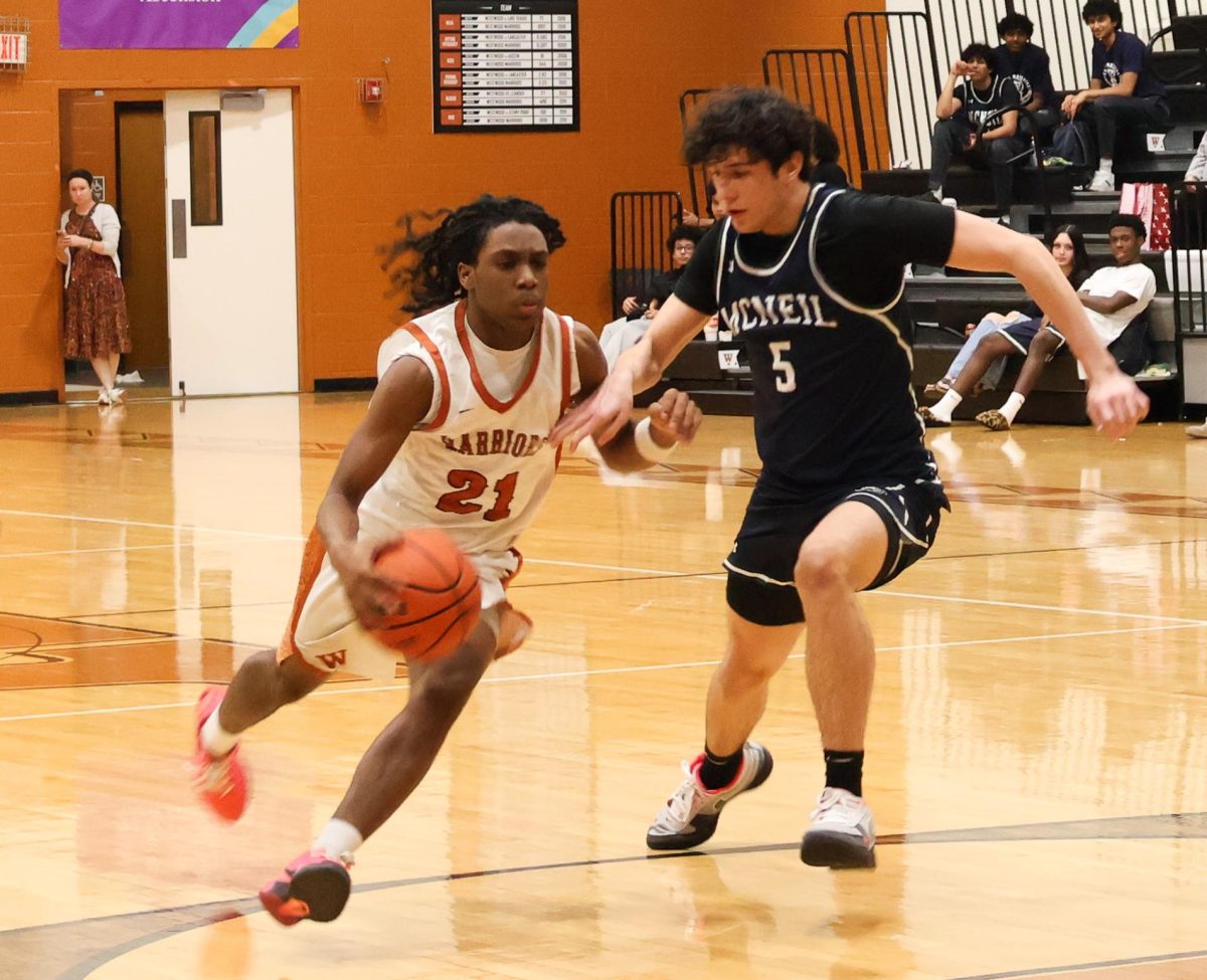 Kameron Hill '29 drives toward the basket while being closely guarded by a McNeil defender. Hill '29 fought through contact to create an offensive opportunity for the Warriors.