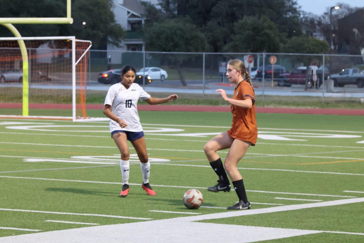 Focusing ahead, Isabella Keckler '27 prepares to kick the ball to evade the incoming opponent. Warrior offense had to utilize footwork to move past the defense set up by the Mavericks. 