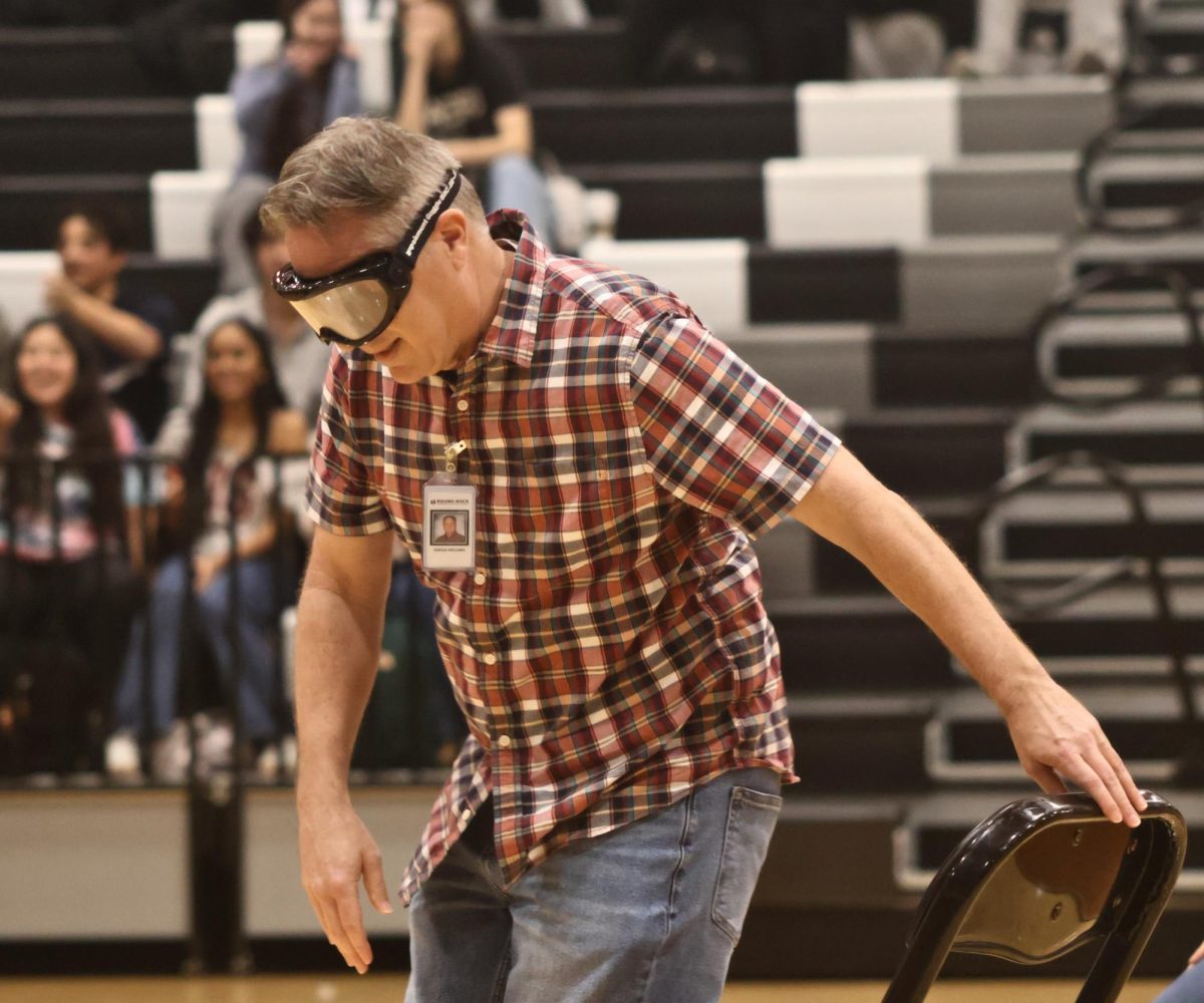 Holding a chair, Advanced Placement (AP) Human Geography teacher Joshua Williams from the Red Team secures himself a seat when the music stopped. As soon as the music paused, teachers raced to grab a seat in fear of losing to their opponents.
