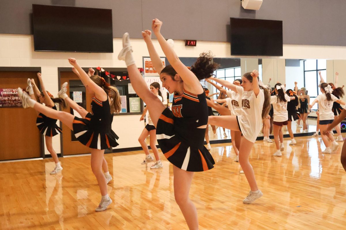 Performing a high-kick, Isabella Cunningham '27 guides the middle school cheerleaders through the fight song. The cheerleaders led by example by smiling and being kind to your teammates no matter what may occur.