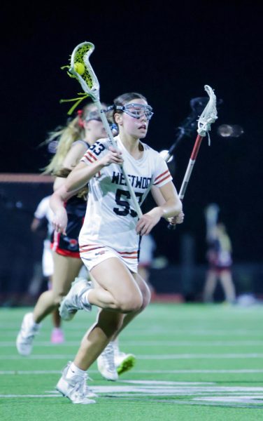 Moving down the field, Bonnie Rose Hance '29 cradles the ball, defenders behind her. As the only freshman on the Varsity team, Hance was able to use the season opener to sharpen her lacrosse skills for the season ahead. 
