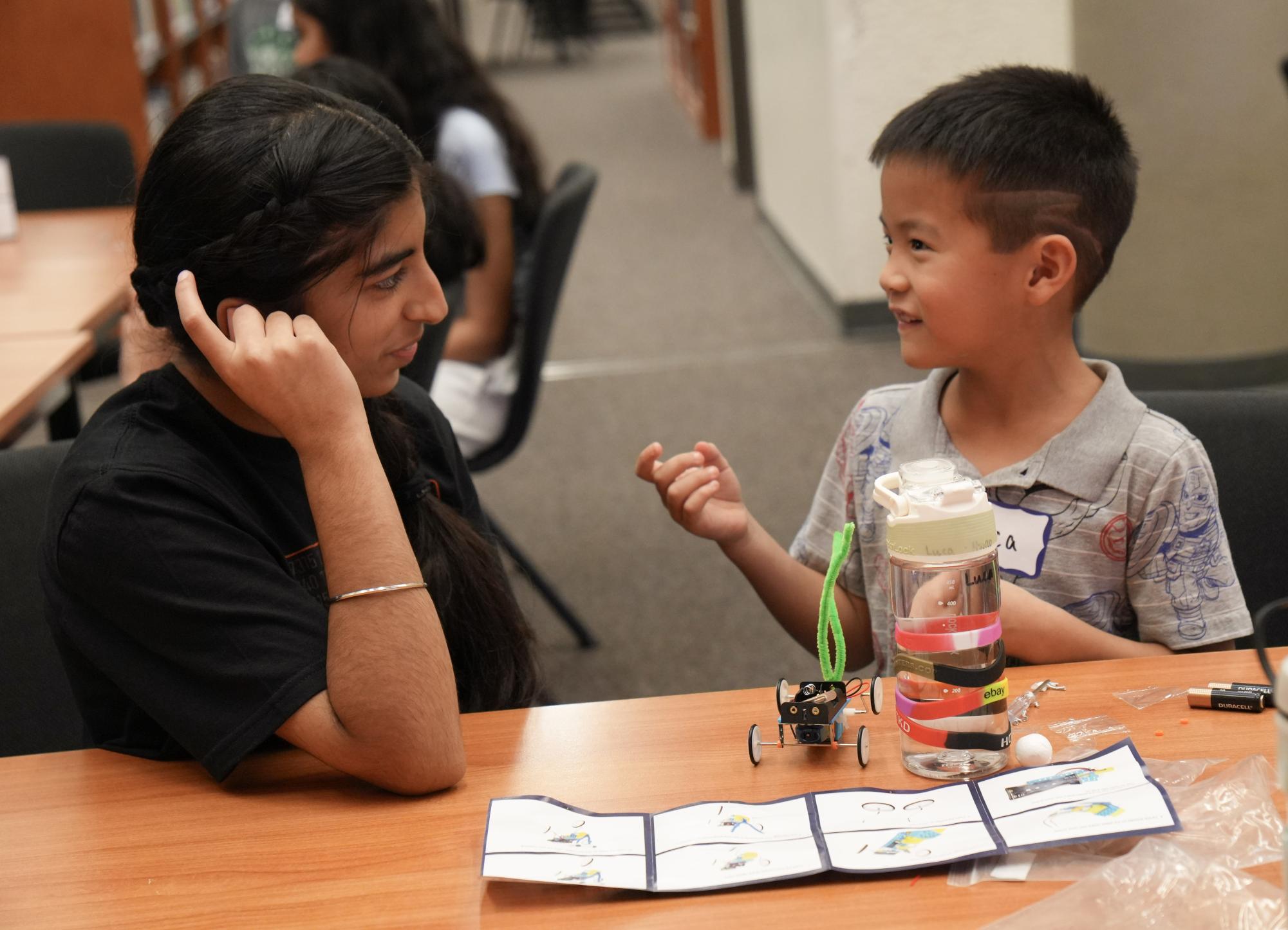Attentively, Reett Aulakh '28 listens to an attendee's explanation of his custom car. Aulakh was one of the many FIRST Robotics Competition (FRC) volunteers that pitched in for the Minibots event. 