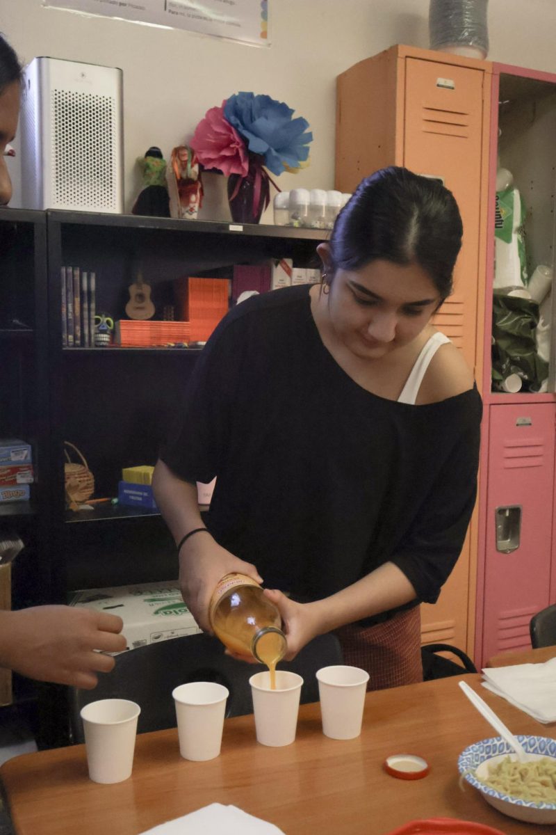 Focused, South Asian Student Association (SASA) officer Lakshmi Trivedi '27 prepares the spread for the meeting. The officers brought premade Maggi noodles from home and mango juice to give out to members during the meeting. 