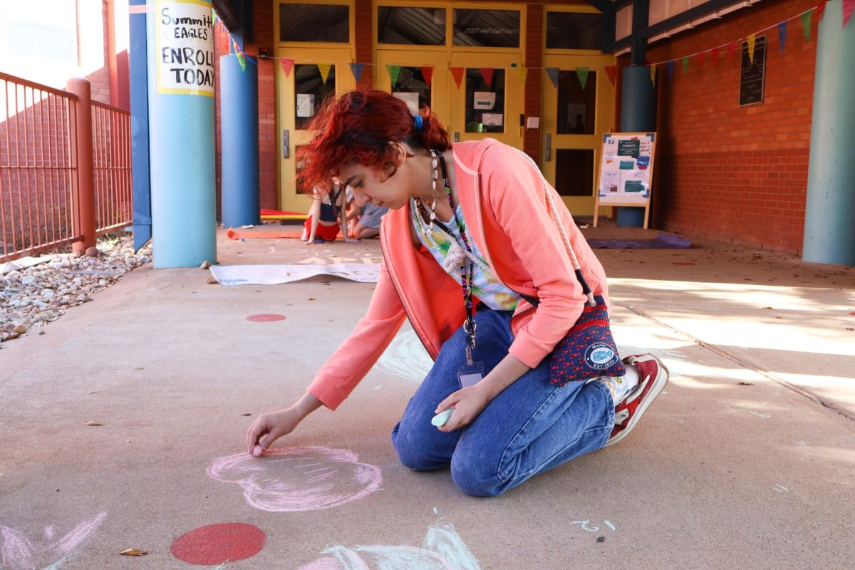 Focused on the chalk strokes, Abrielle Smith '26 draws intricate details of an apple. Inspired by story books she read when she was in elementary school, she drew images of nature that reminded her of her childhood. "I've been allowing the colors to guide me as I go," Smith said.